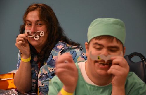 two people smiling holding up cardboard mustache props