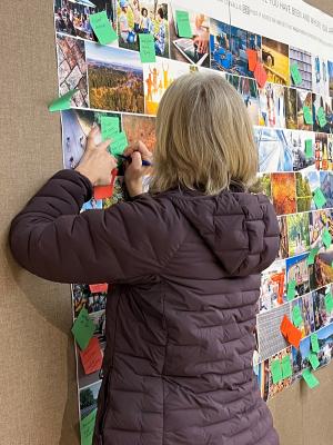 A community member writes on a post-it note at the open house