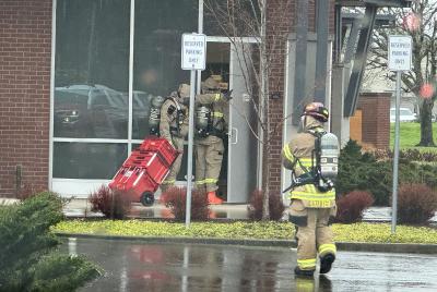 Firefighters wearing hazardous materials gear make entry into Oregon State Credit Union.