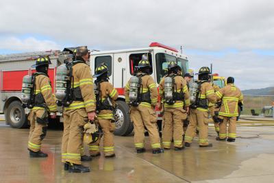 Firefighters in turnout gear standing near a red fire engine